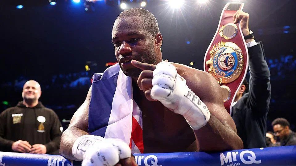 Daniel Dubois leans over the ropes of a boxing ring and holds up one finger